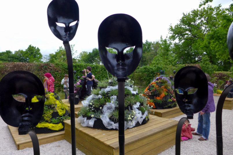 Masques noirs regardant des robes de fleurs. On peut placer son visage derrière les robes ou derrière les masques.